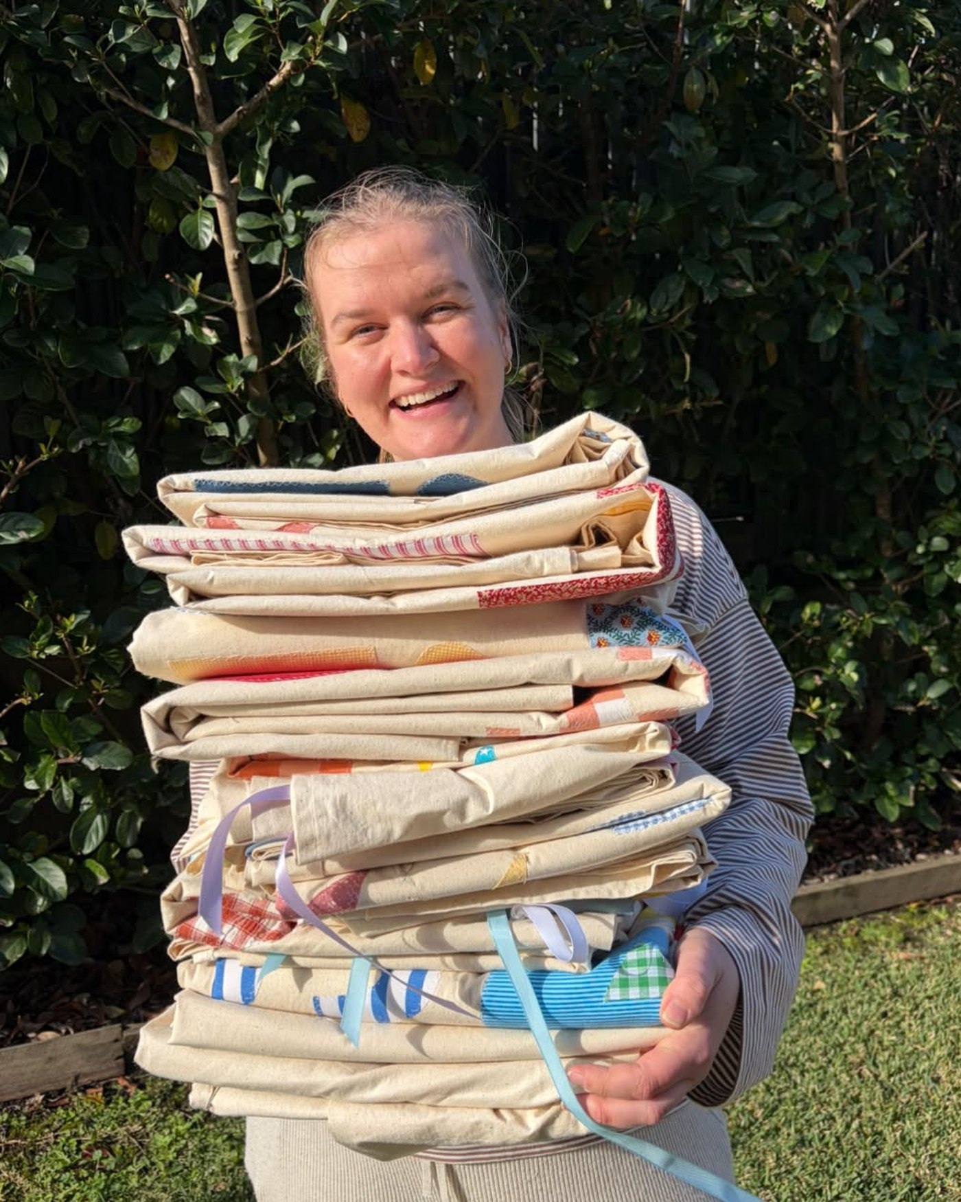 Lydia holding a stack of finished banners almost up to her chin, grinning over the top of it.