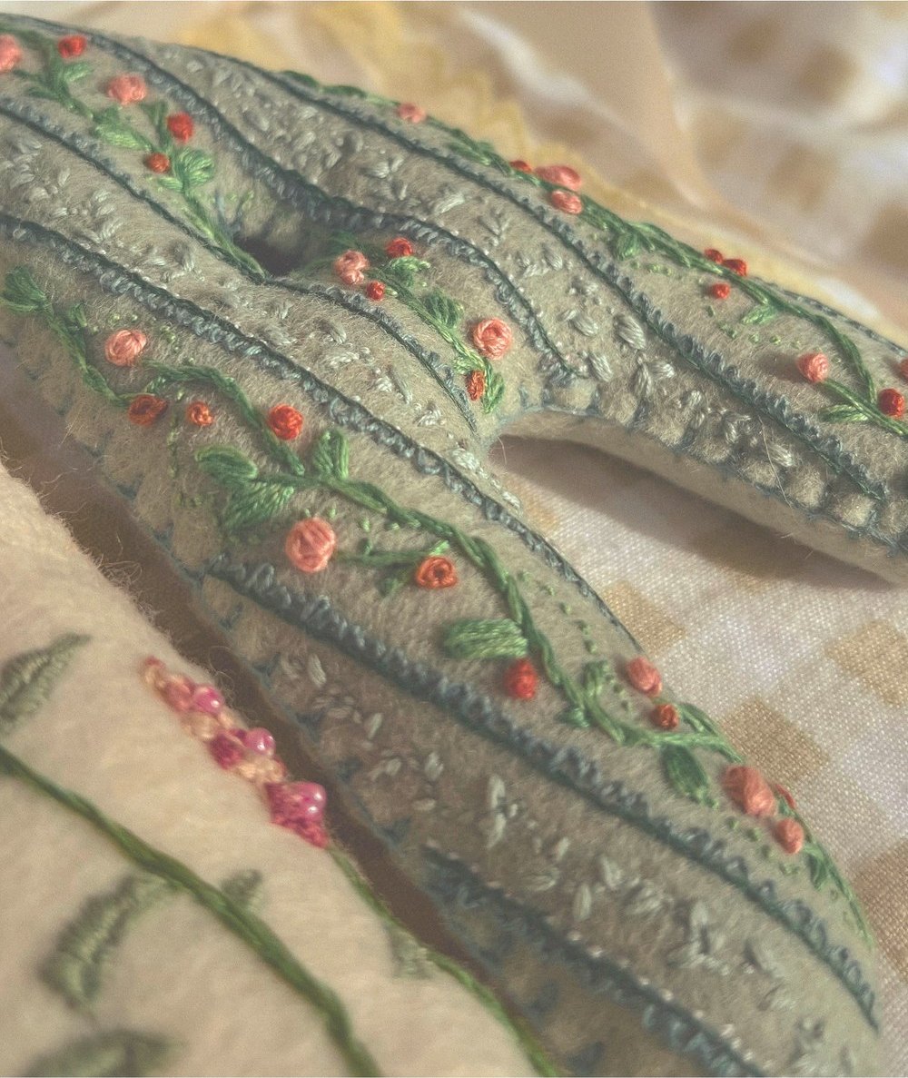 A sage felt letter embroidered with trailing roses and tiny beads