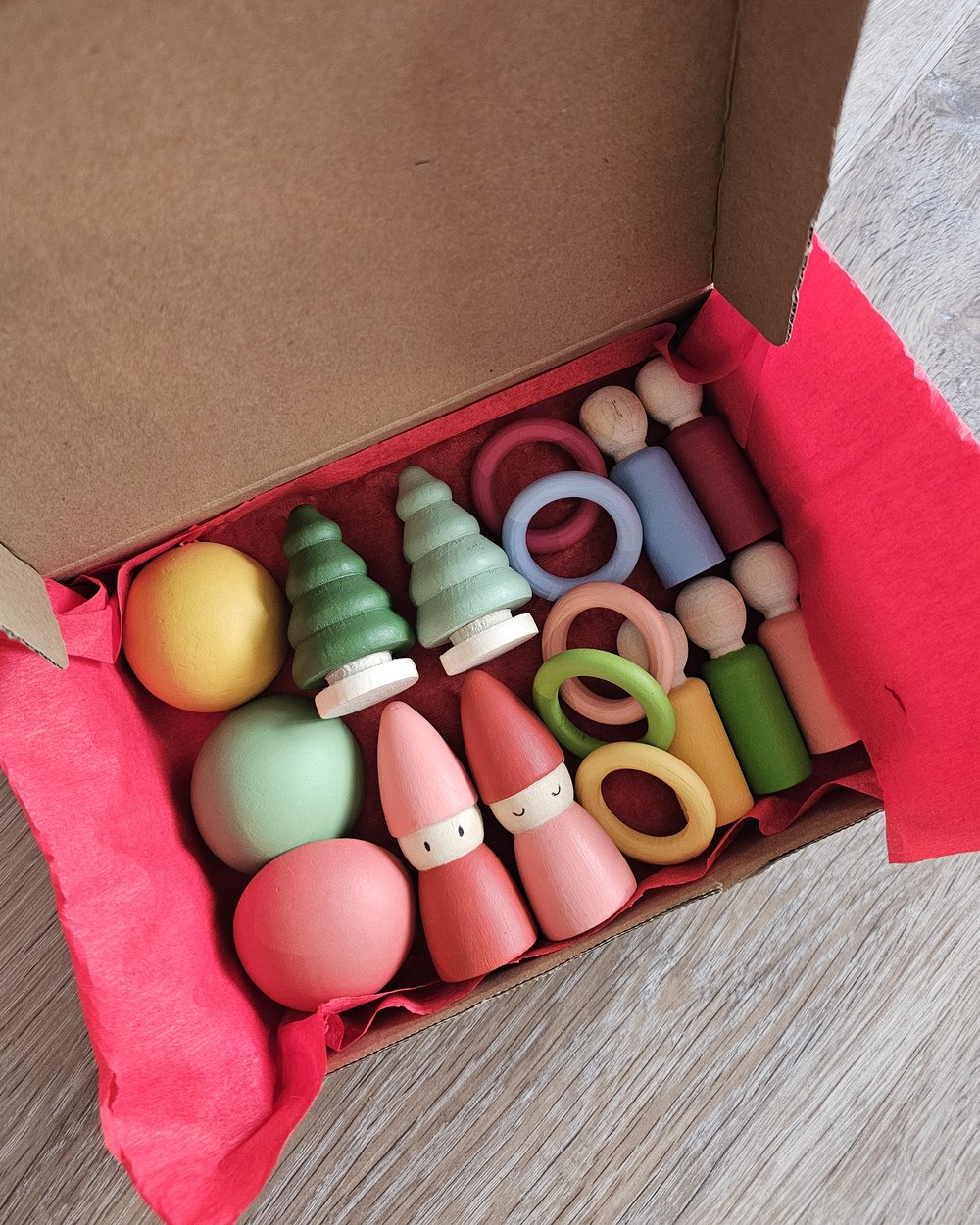 An order packed into a box with red tissue paper, gnomes, trees, rings and domes inside