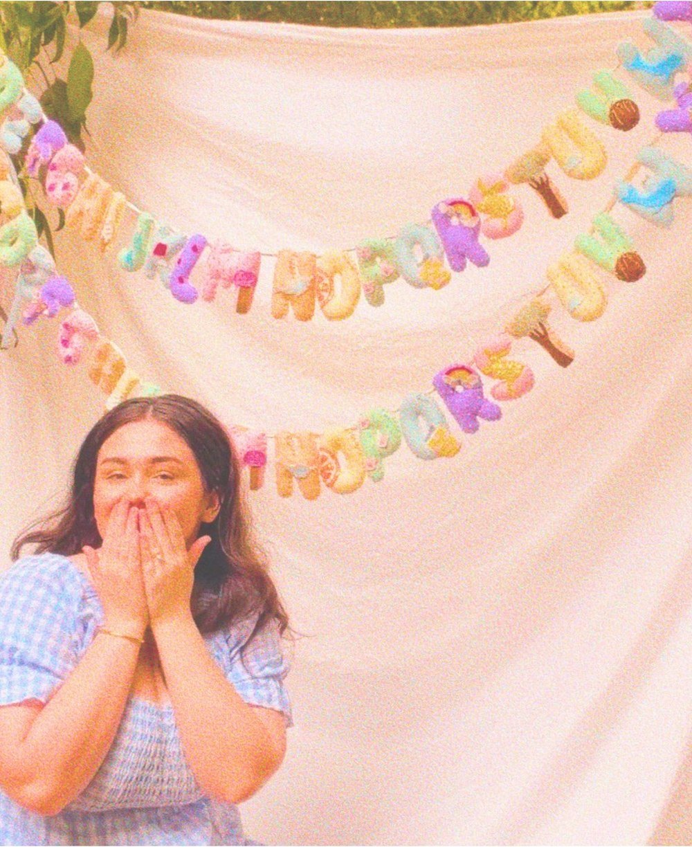 Amy laughing in front of two full alphabet banners hung on a sheet outdoors