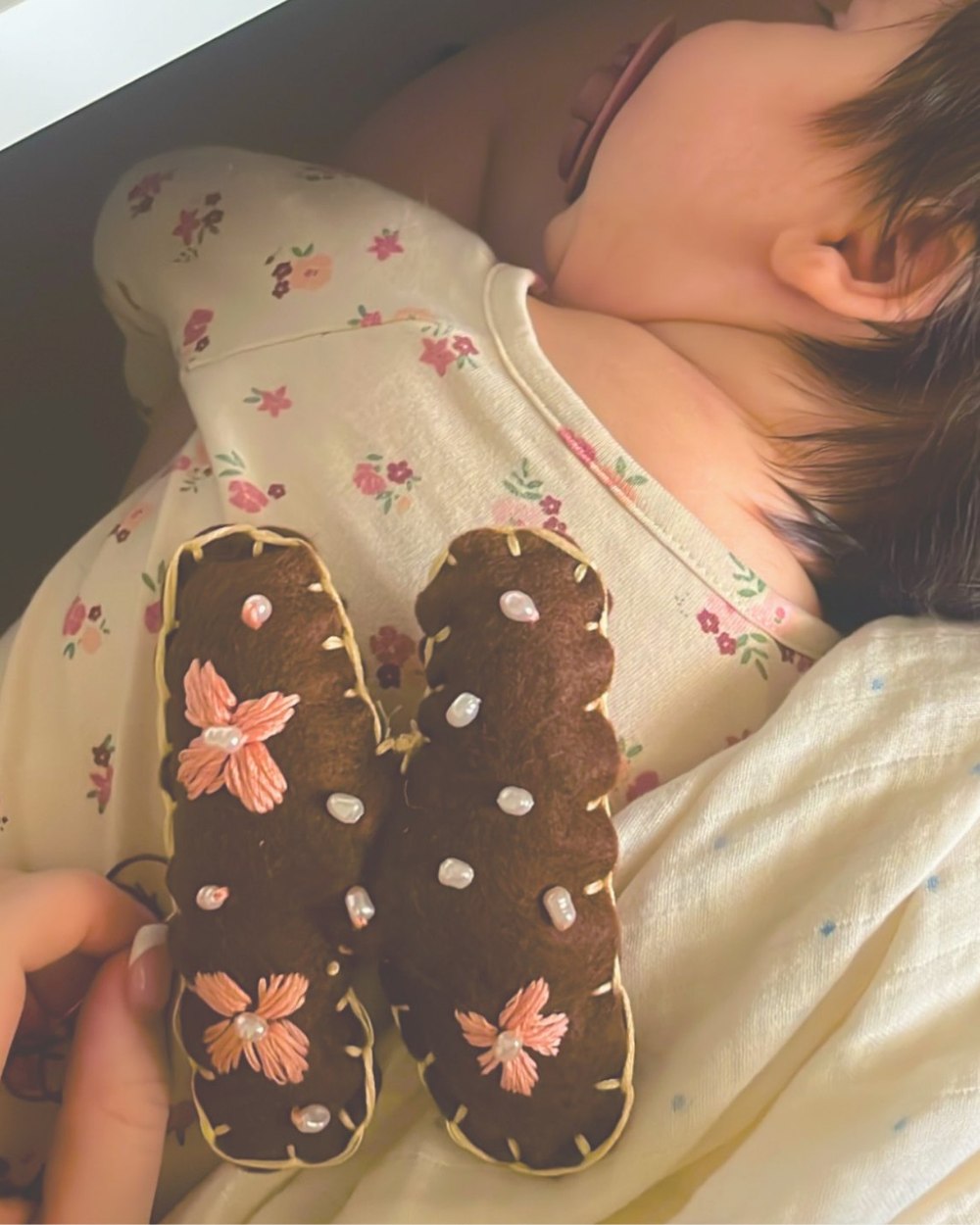 A sleeping baby with a beaded felt letter resting on her chest
